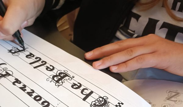 Dettaglio delle mani di una studentessa che esegue prove di calligrafia