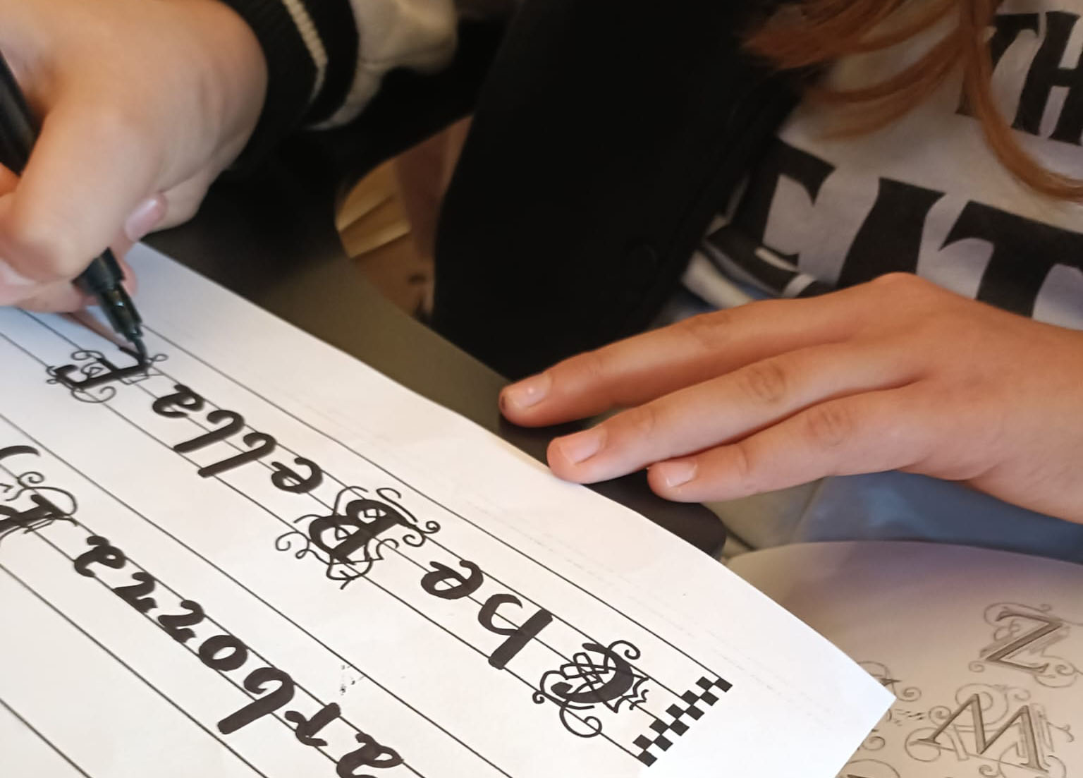 Dettaglio delle mani di una studentessa che esegue prove di calligrafia